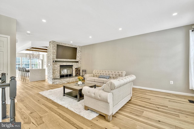 living room with recessed lighting, baseboards, light wood-style floors, and a stone fireplace