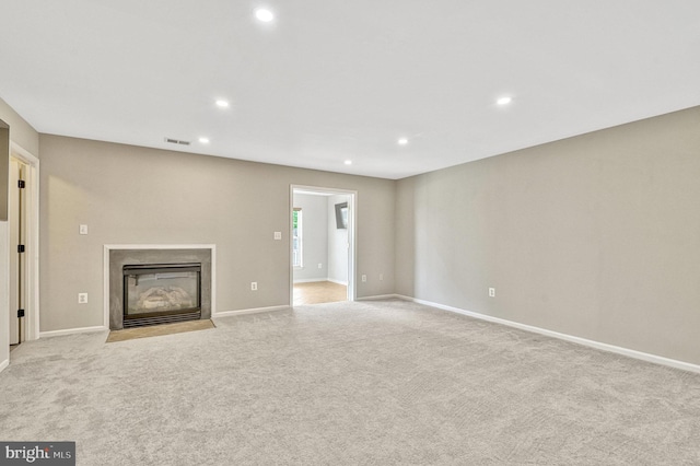 unfurnished living room featuring a fireplace with flush hearth, recessed lighting, visible vents, and light carpet