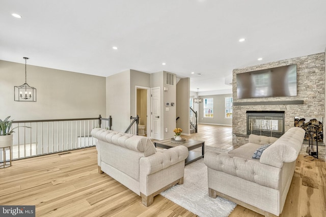 living area with visible vents, a fireplace, an inviting chandelier, and wood finished floors