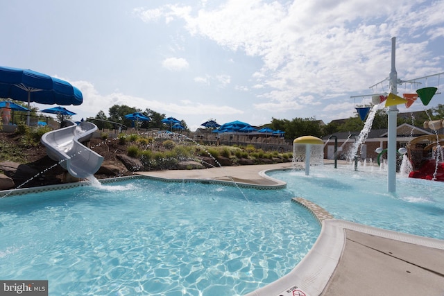 community pool featuring fence and a water slide