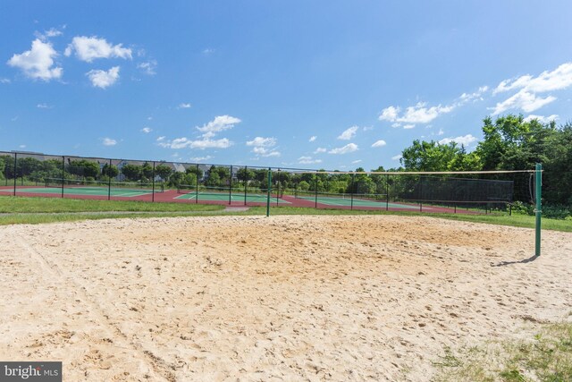 view of home's community with volleyball court, a tennis court, and fence