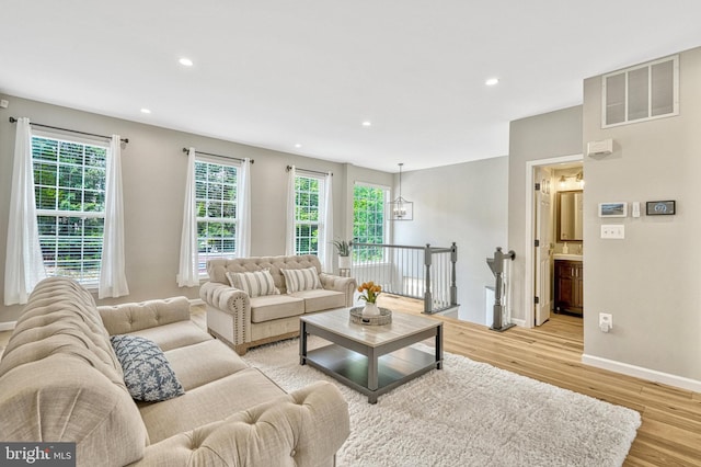 living room featuring baseboards, recessed lighting, visible vents, and light wood-type flooring