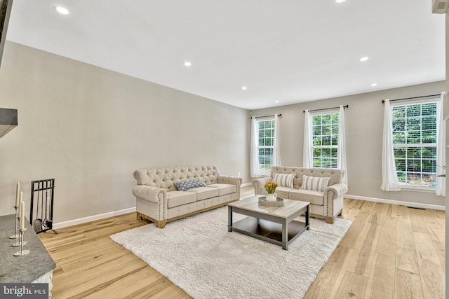 living area with recessed lighting, visible vents, baseboards, and light wood finished floors