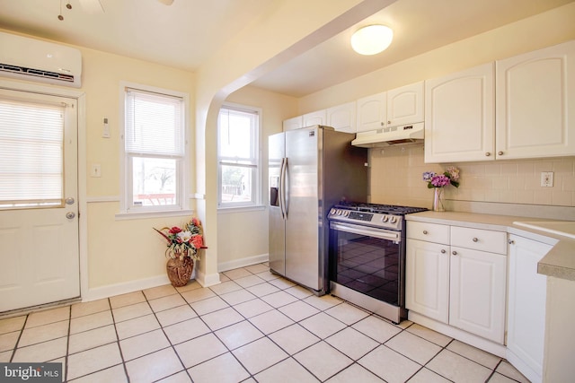 kitchen featuring under cabinet range hood, appliances with stainless steel finishes, tasteful backsplash, and a wall unit AC