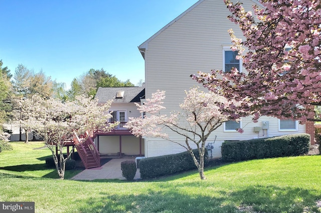 exterior space with a patio, a lawn, a wooden deck, and stairway