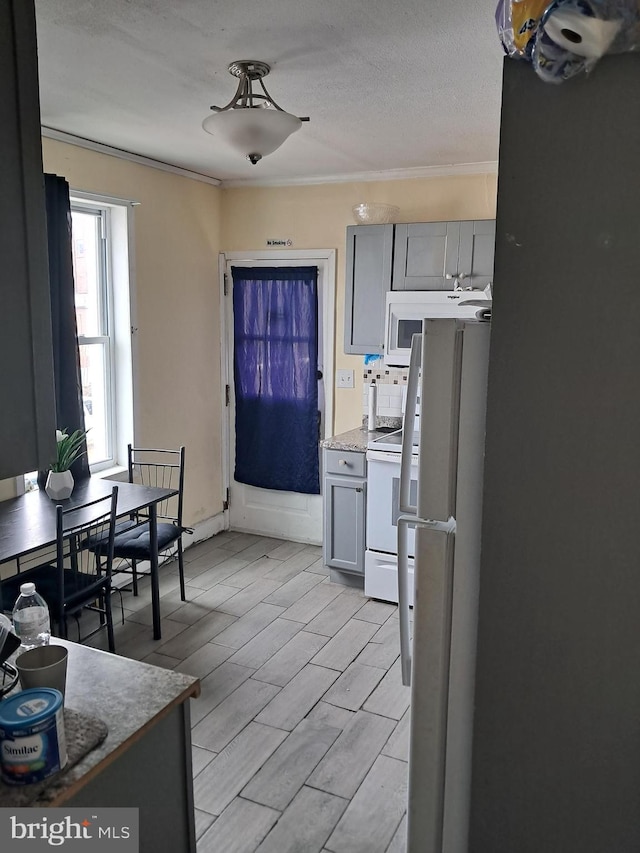 kitchen featuring gray cabinetry, crown molding, wood tiled floor, white appliances, and a textured ceiling