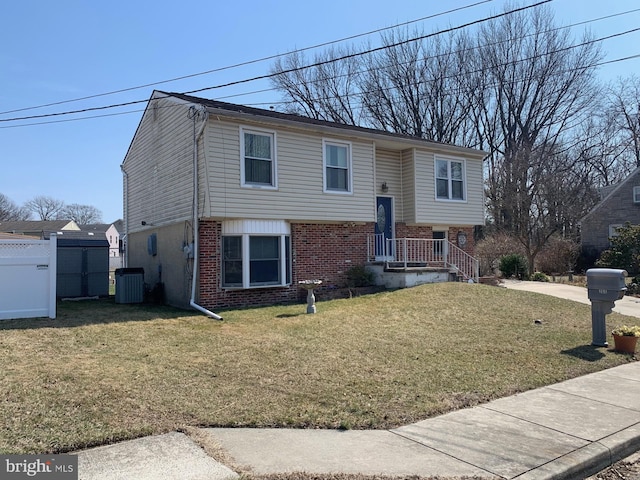 split foyer home with brick siding, a front lawn, and fence