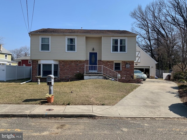 raised ranch with a garage, brick siding, a front lawn, and fence