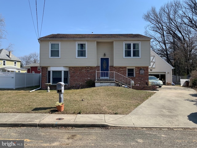 bi-level home with brick siding, a garage, a front yard, and fence