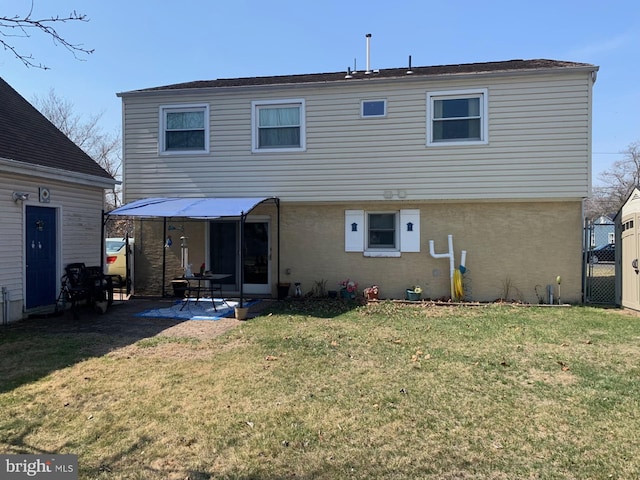 rear view of house with brick siding, a patio area, and a lawn