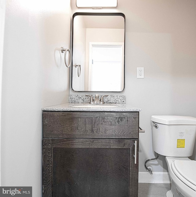 half bathroom with vanity, toilet, and baseboards