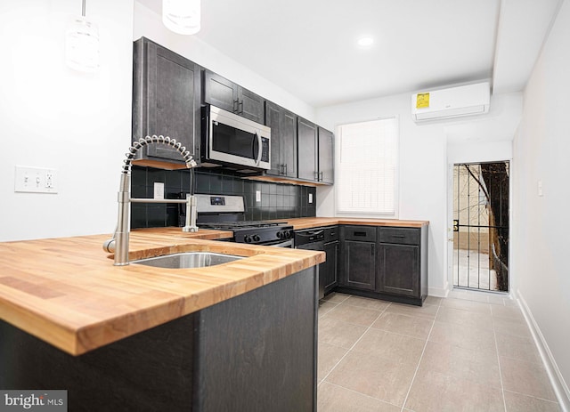 kitchen featuring butcher block counters, an AC wall unit, light tile patterned floors, decorative backsplash, and stainless steel appliances