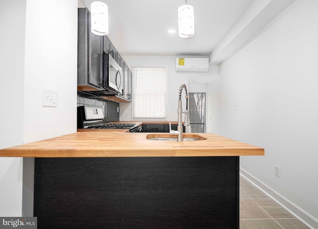 kitchen with gas stove, a peninsula, a sink, a wall mounted air conditioner, and stainless steel microwave