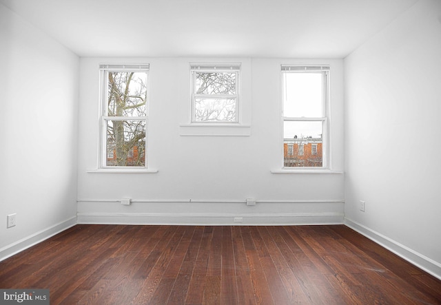 empty room featuring baseboards and dark wood-style flooring