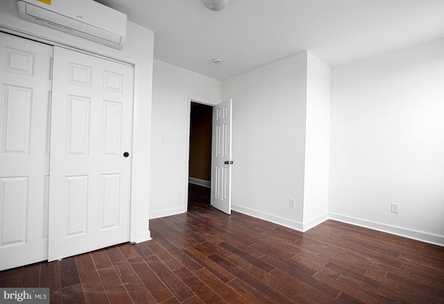 unfurnished bedroom featuring baseboards, dark wood-style flooring, and a wall mounted AC