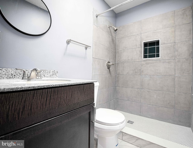 full bath with a tile shower, marble finish floor, toilet, and vanity