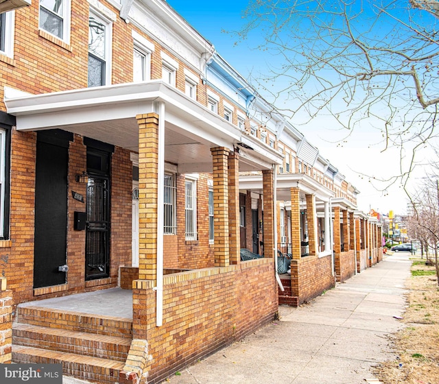 view of side of property featuring brick siding and covered porch