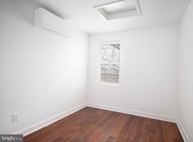 empty room featuring attic access, dark wood-style floors, baseboards, and a wall mounted AC