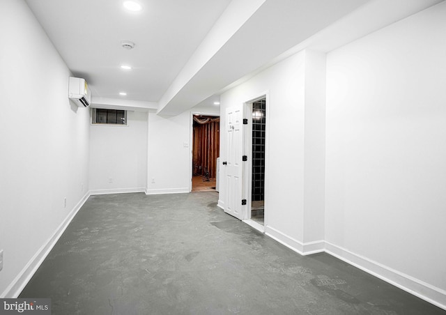 finished below grade area featuring a wall mounted air conditioner, baseboards, and recessed lighting