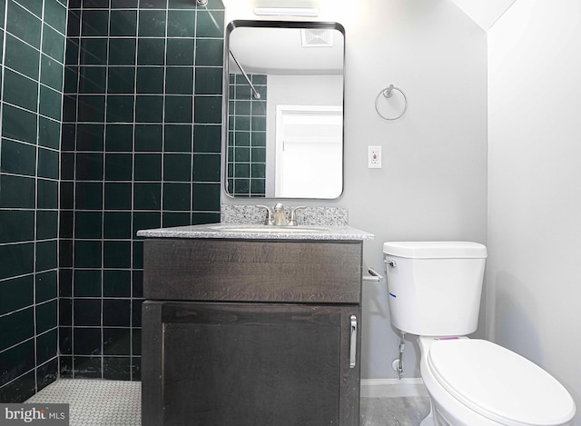 full bathroom with baseboards, toilet, vanity, and a tile shower