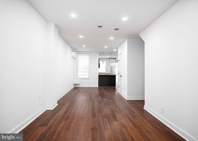 unfurnished living room with dark wood finished floors, recessed lighting, and baseboards