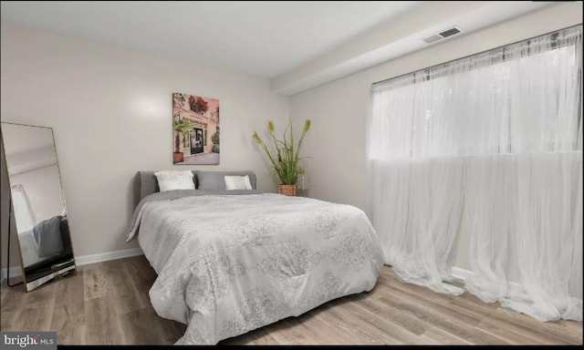 bedroom with visible vents, baseboards, and wood finished floors