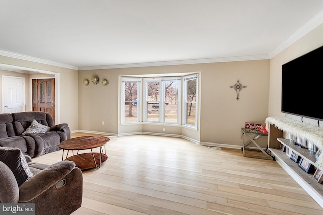 living room featuring visible vents, light wood-style flooring, baseboards, and ornamental molding