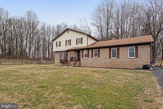 view of front of house with brick siding, a chimney, a front yard, and fence