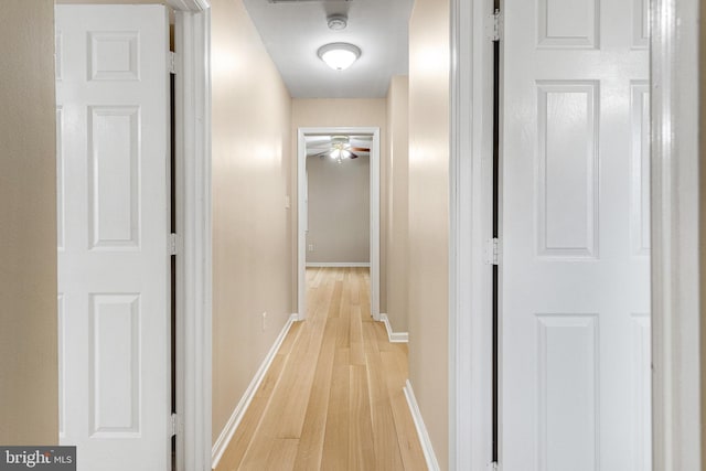 corridor featuring light wood-type flooring and baseboards