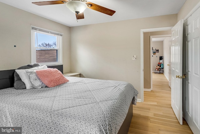 bedroom with light wood-style flooring, a ceiling fan, and baseboards