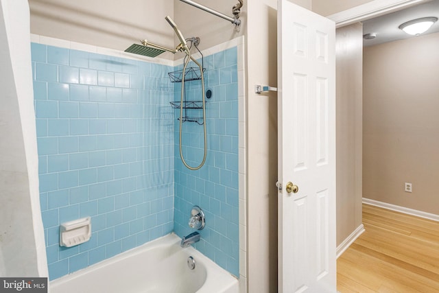 bathroom with baseboards, bathing tub / shower combination, and wood finished floors