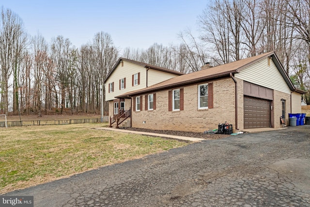 view of side of home featuring a garage, brick siding, a chimney, and aphalt driveway