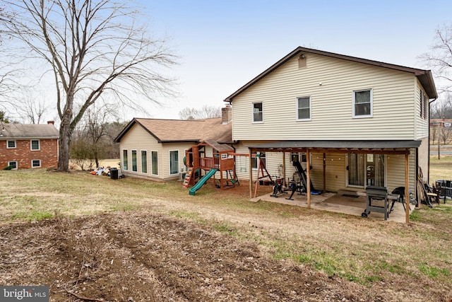 back of property with a yard, a playground, and a patio