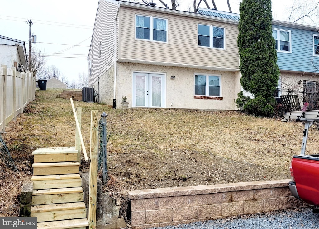 view of front facade with stairs, central air condition unit, stucco siding, and fence