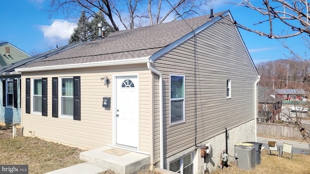 exterior space with roof with shingles, central AC, and fence