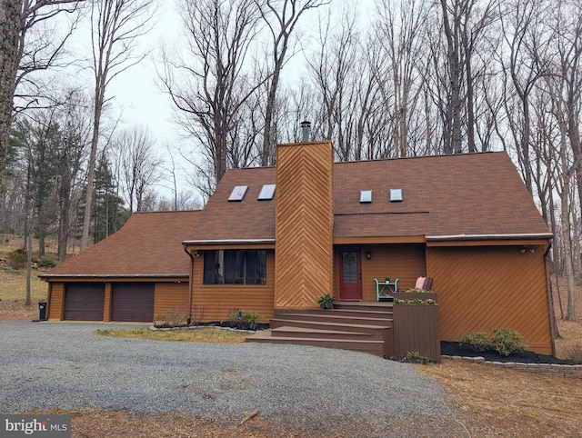 view of front of property with driveway, a chimney, a garage, and a shingled roof