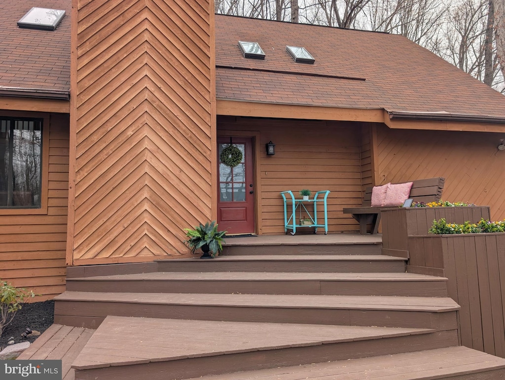 property entrance featuring roof with shingles and a porch