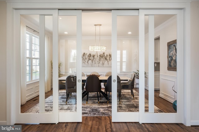 interior space featuring an inviting chandelier, wood finished floors, crown molding, and a wainscoted wall