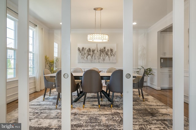 dining area with ornamental molding, wainscoting, a wealth of natural light, and wood finished floors