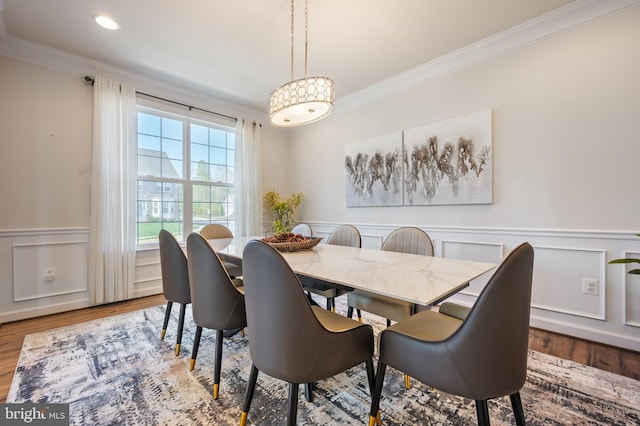 dining room with wainscoting, ornamental molding, and wood finished floors