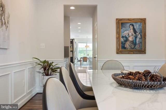 dining space with dark wood finished floors, recessed lighting, a wainscoted wall, and a decorative wall