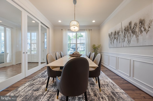 dining area with crown molding, a wainscoted wall, a decorative wall, and dark wood finished floors