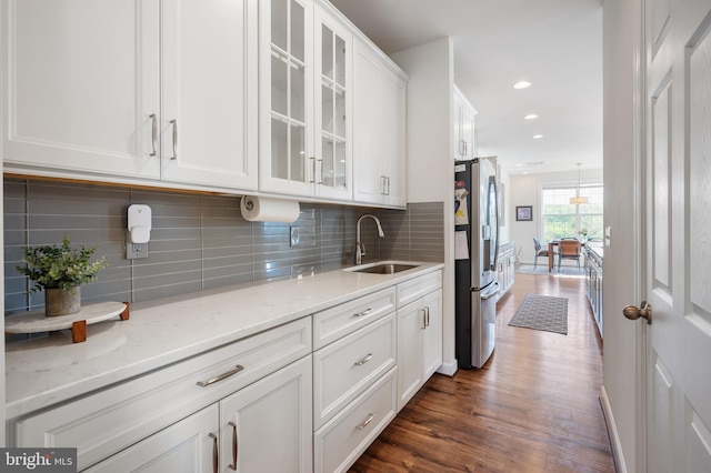 kitchen with decorative backsplash, stainless steel fridge with ice dispenser, a sink, white cabinetry, and dark wood-type flooring