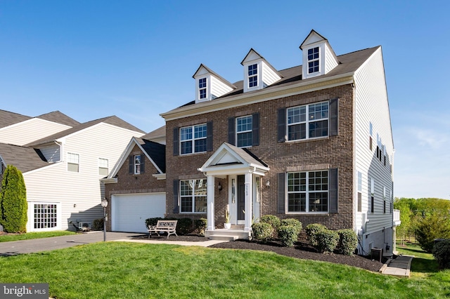 view of front of home with brick siding, a front yard, and concrete driveway