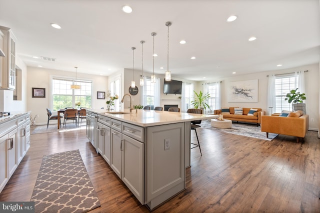 kitchen featuring recessed lighting, a sink, dark wood-style flooring, a kitchen bar, and visible vents