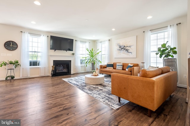 living room featuring baseboards, recessed lighting, wood finished floors, and a fireplace with flush hearth