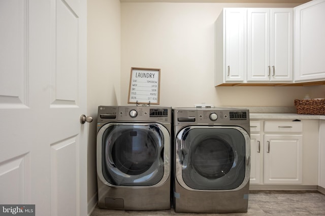 washroom with light wood-style floors, cabinet space, and washing machine and clothes dryer