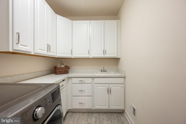 laundry area featuring a sink, visible vents, light wood finished floors, cabinet space, and washer / dryer