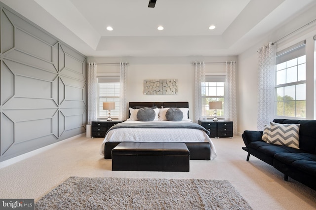carpeted bedroom featuring recessed lighting and a raised ceiling