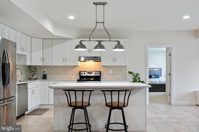 kitchen with light tile patterned floors, light countertops, stainless steel appliances, and under cabinet range hood